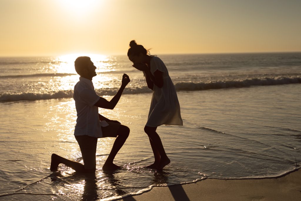 Romantic man proposing woman at seashore on the beach